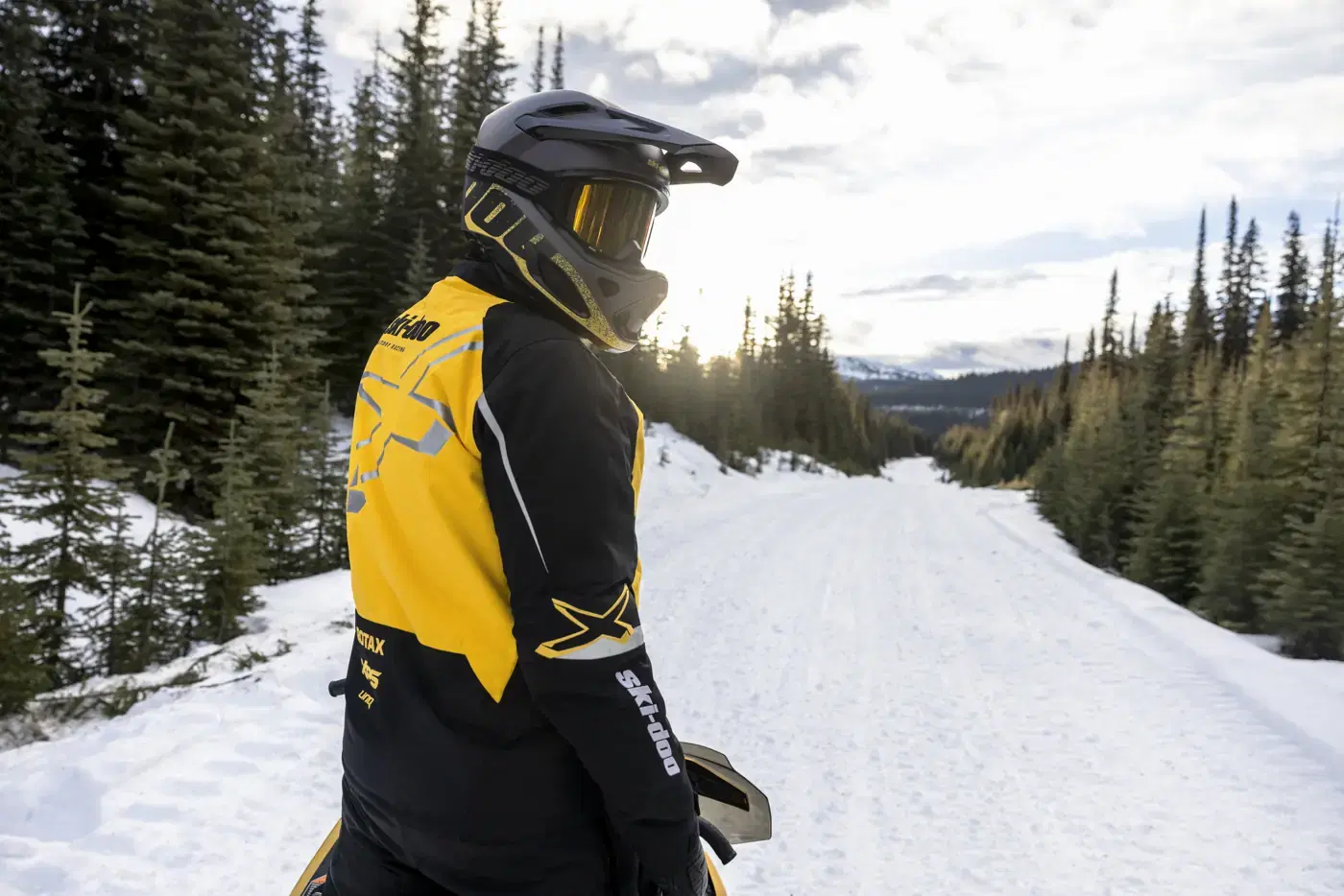 Motoneigiste en manteau Ski-Doo jaune sur un sentier