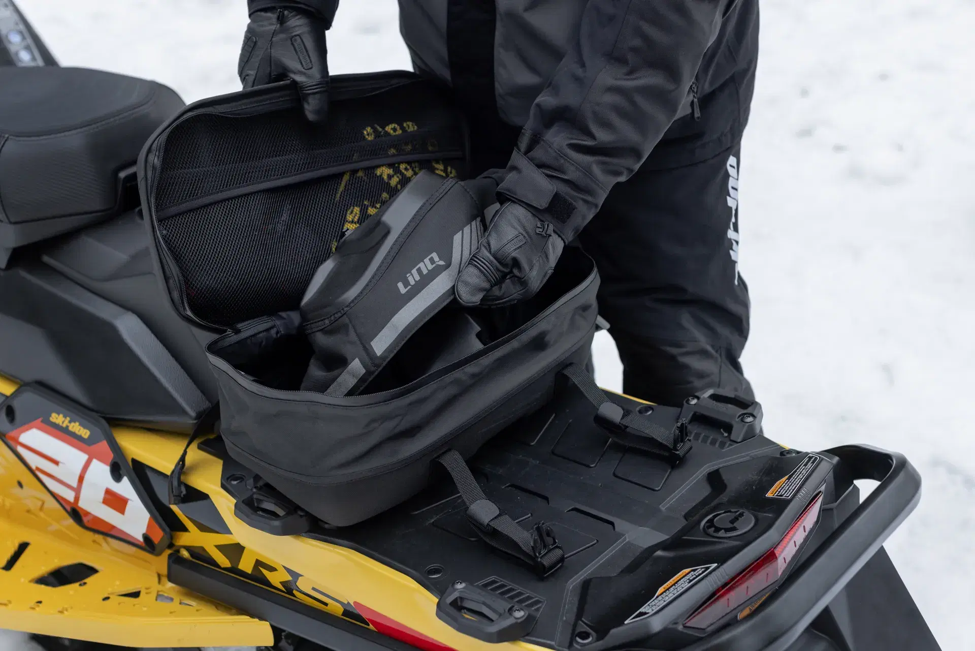 Motoneigiste ouvrant un sac LinQ sur une Ski-Doo Renegade X-RS 2027